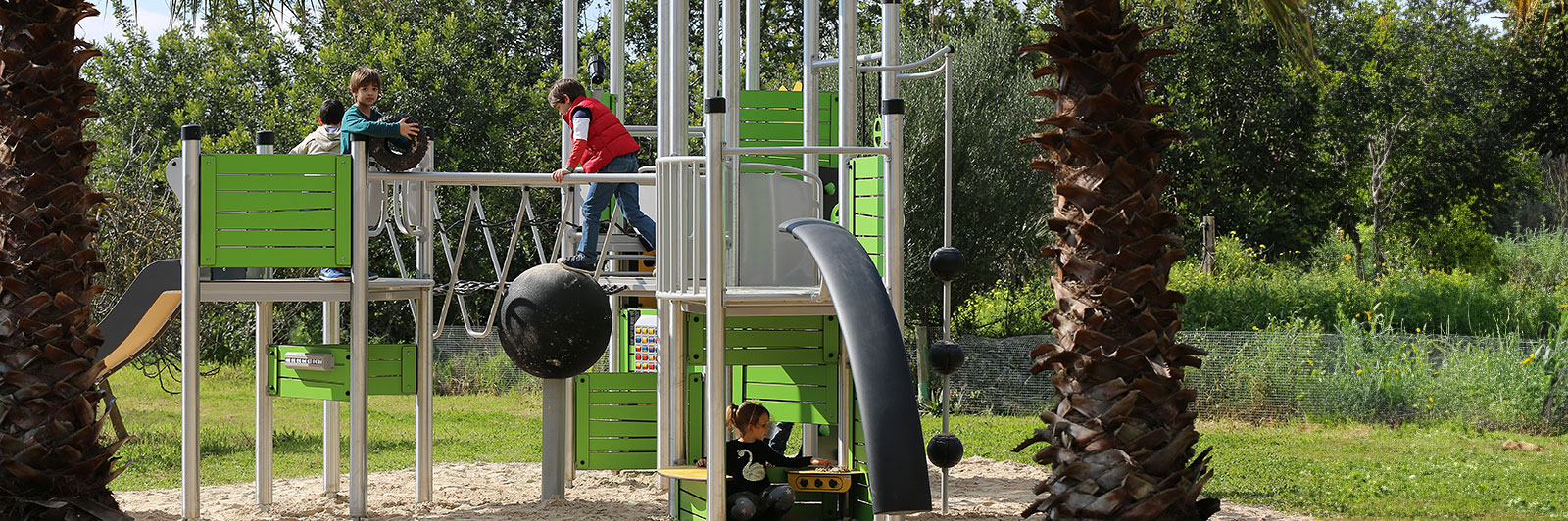 Children play at a large steel playground unit, which is mostly made out of steel with green HPL panels.